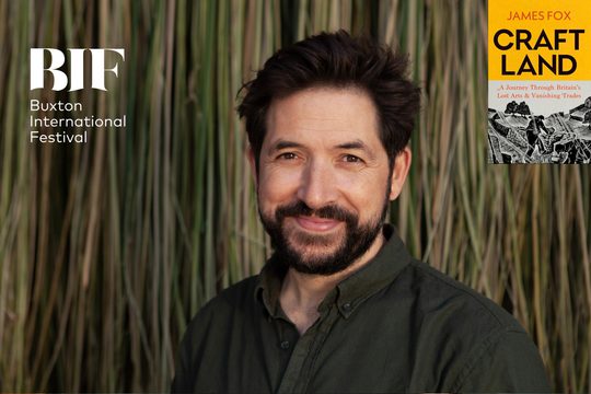 Man with dark hair and beard smiles to camera in front of bamboo shoots.