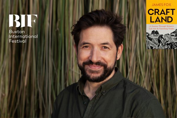 Man with dark hair and beard smiles to camera in front of bamboo shoots.