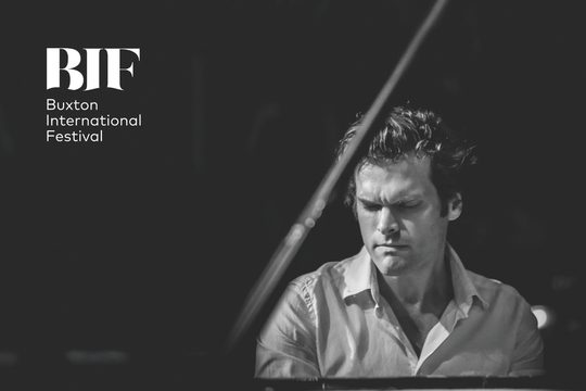 Black and white image of a man playing the piano and concentrating.