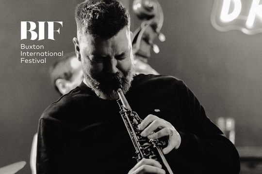 Black and white image of a man playing a saxophone.