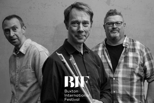 A black and white image of three men smiling straight at the camera.