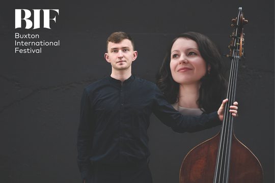 Man has a double bass next to larger image o a woman with dark hair.