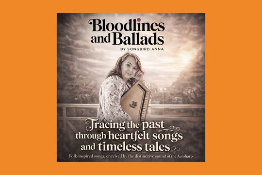 A grey image of a white woman holding a harp-like instrument. Text: Bloodlines and Ballads by Songbird Anna. Tracking the past though heartfelt songs and timeless tales.