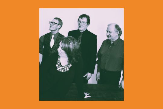 Black and white image of three men and one woman looking over to one side.