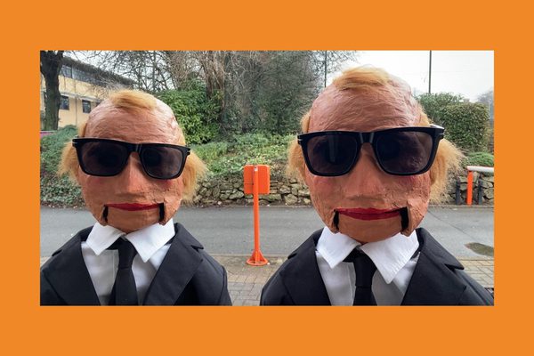 Two papier mache heads with sunglasses wearing suits.