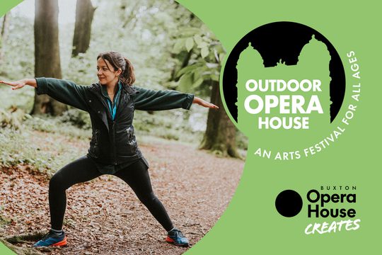 A woman doing yoga in the woods. She is lunging and has her arms out straight at either side of her.