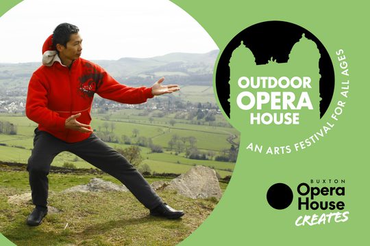 A man in a red coat doing tai chi on top of a hill.