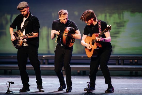 Three musicians play the banjo, drum, and guitar.