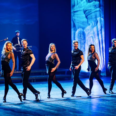 A group of dancers all standing in a straight line.