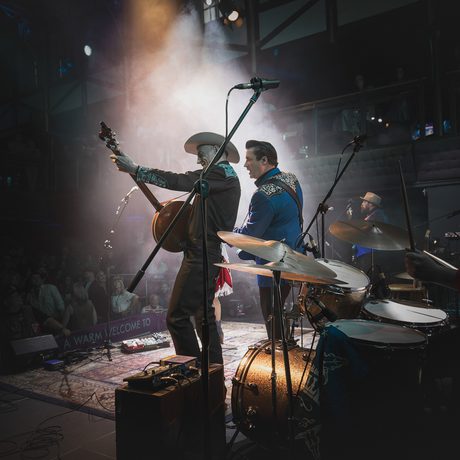 Two musicians from behind, lit by a spotlight.