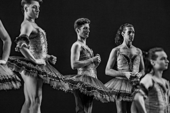 Black and white image of male ballet dancers wearing tutus rehearsing.