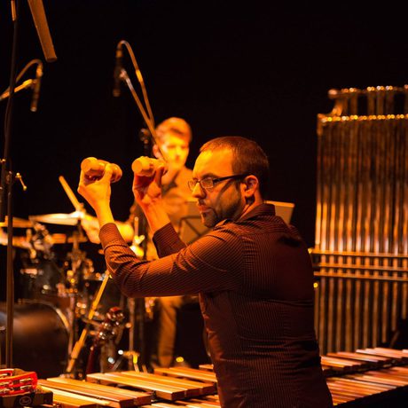 A man playing shakers lit by orange lighting.
