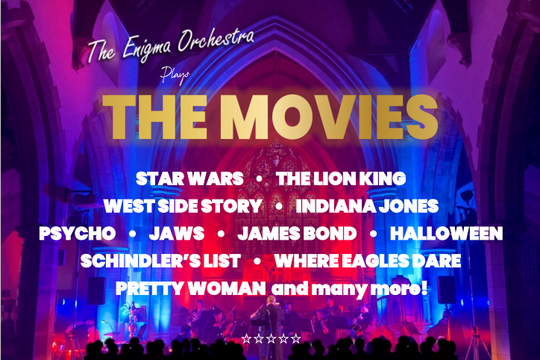 An orchestra playing in a church surrounded by dramatic lighting.