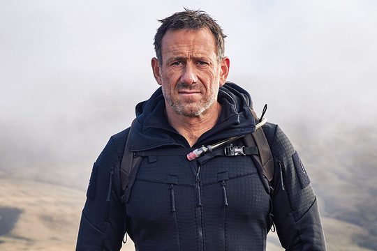 Jason fox at the top of a hill with mist behind him