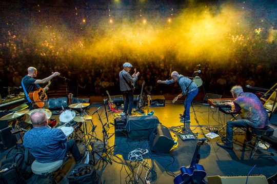 the stage from above bright yellow lights shine of a blue cast band as they play