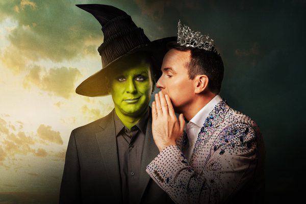 Two versions of Matt Forde. One is painted green with a witch's hat. One is wearing a pink sparkly jacket and a tiara, and is whispering to the other.