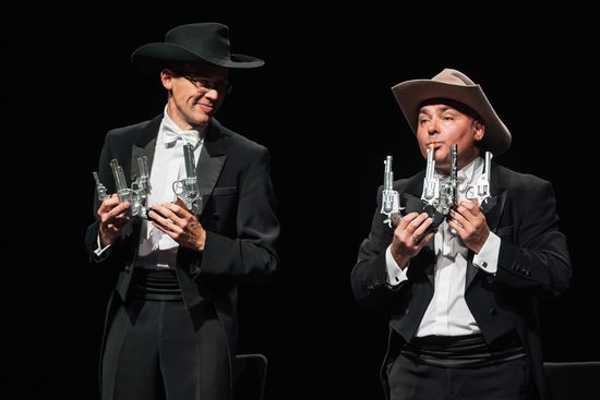 Two men in cowboy hats playing instruments made out of fake guns.