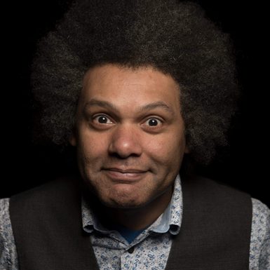 A man with an afro smiling at the camera.