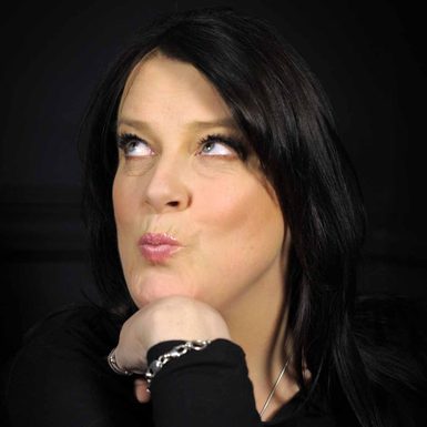 A woman with black hair rests her head on her hand and pouts her lips.