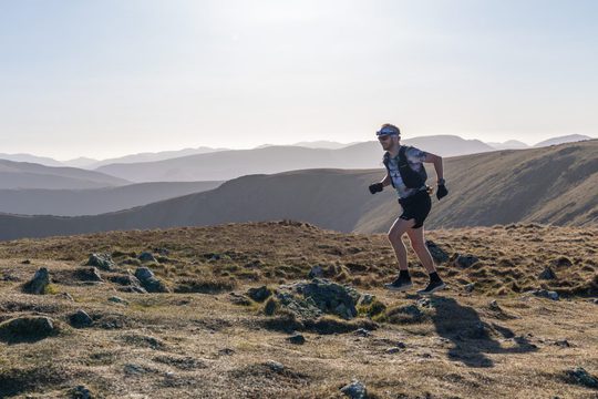 Man in shorts and t-shirt runs across hilltop
