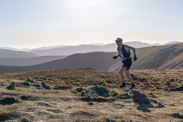 Man in shorts and t-shirt runs across hilltop