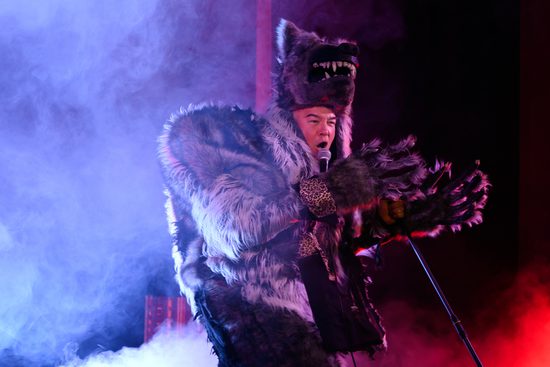 A man dressed as a wolf speaking into a microphone.