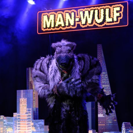 A large wolf standing in front of a model city and a sign that says "Man-Wulf"