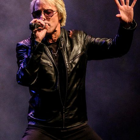 Performer in leather jacket sings into microphone