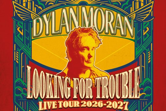 A yellow background with a yellow and red image of an older man. The image is surrounded by text that says "Dylan Moran: Looking for Trouble".