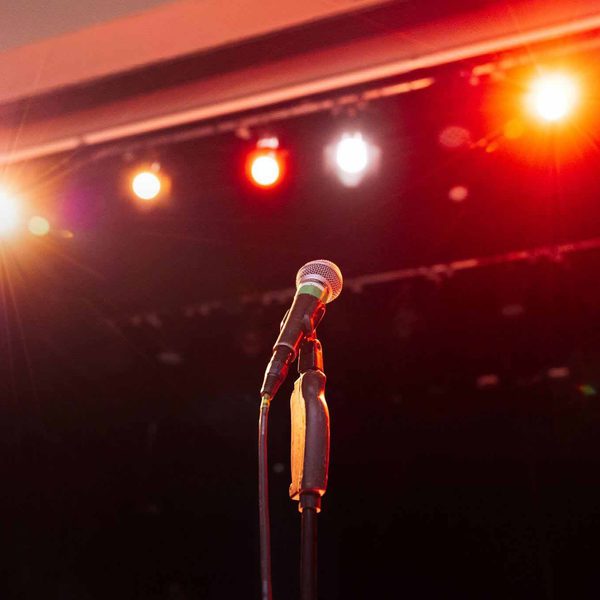 A microphone on a stand with spotlights in the background.