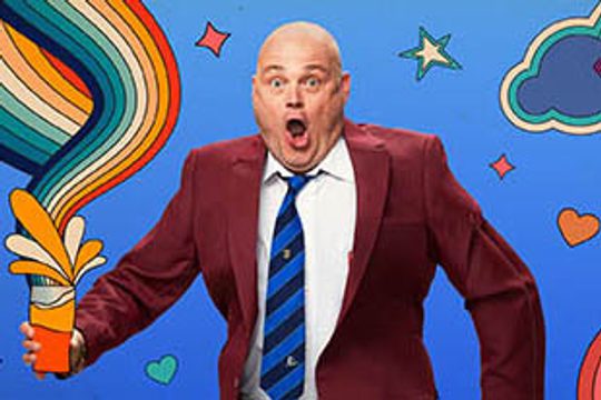 Al Murray holding a cartoon pint glass with a rainbow coming out of it.