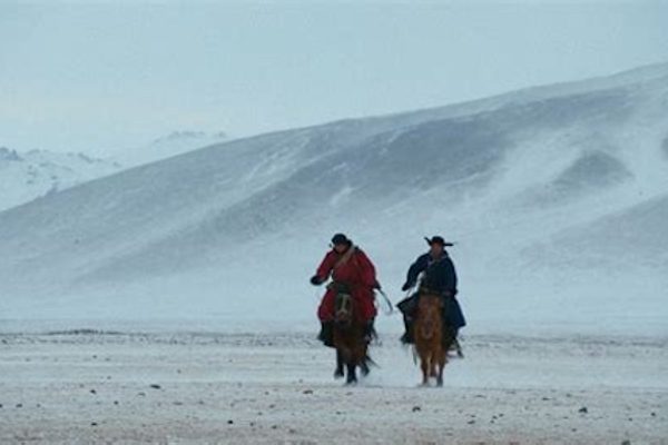 Two men on horses in a snowstorm.
