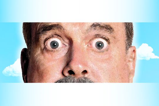 A close-up of an older man's eyes and nose against a blue sky background.
