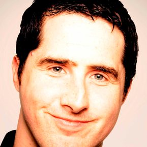 A brunette man smiles directly at the camera.