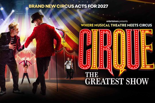 A circus ringleader in a red jacket and black top hat holds hands with a mime. There are other circus performers in the background, in a red and yellow big top. Red and yellow light-up letters: Cirque.
