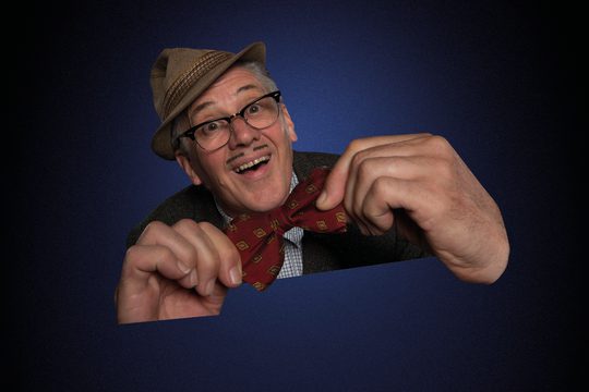 A cut-out of an older man wearing a brown hat holding his red bow tie. It is on a blue background.
