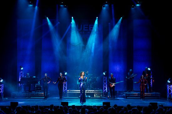 Singers and a band performing on a stage that is lit in bue.