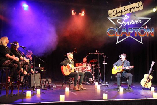 A band playing on stage lit in blue and red lighting.
