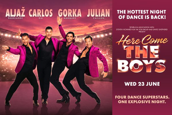A pink background with a full stadium. Four men in black shirts and trousers and bright pink blazers pose in the foreground. Text: Here Come The Boys.