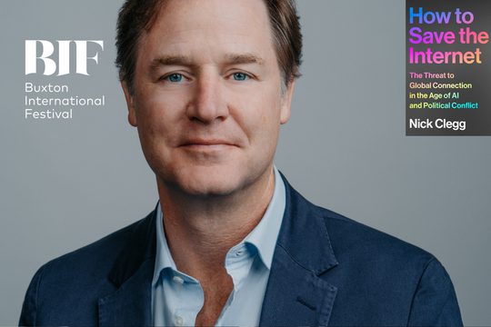 White man with brown hair, wearing a navy blazer against a grey wall.