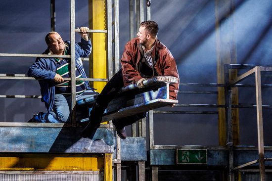 Man straddling a metal bar above the ground as he looks back at someone behind safety bar