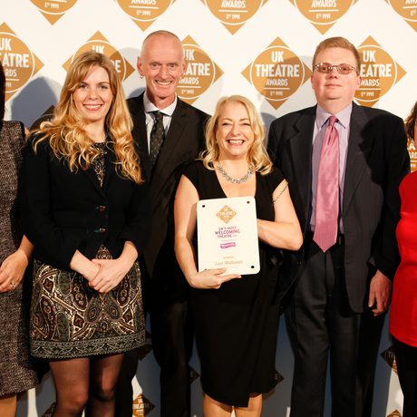 Six members of staff pose with a plaque