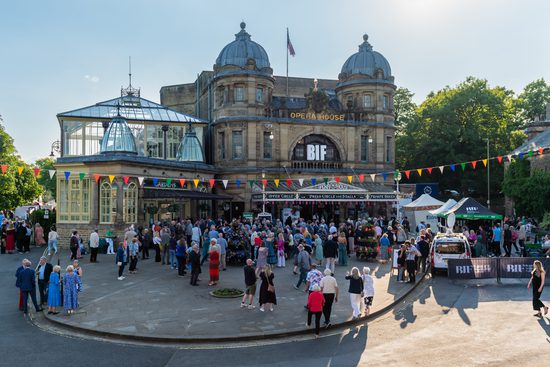 Large crowd of people surround the opera house entrance, bunting lines the street in front