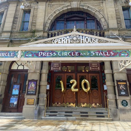 Front steps outside the theatre hold three large balloons reading one hundred and twenty