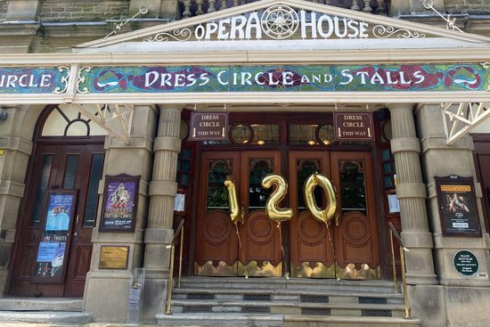 Front steps outside the theatre hold three large balloons reading one hundred and twenty