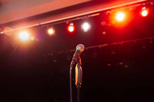 A microphone with stage lights in the background.