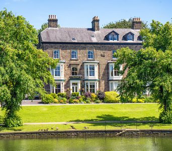 Historic guest house with white bay windows overlooking Pavilion Gardens and lake.